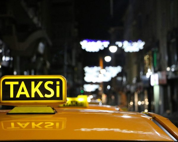 Urban night scene featuring a taxi with glowing lights on a bustling street.