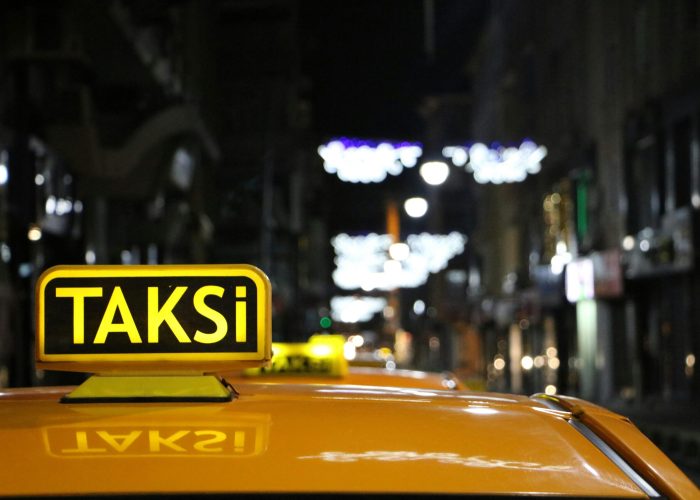 Urban night scene featuring a taxi with glowing lights on a bustling street.